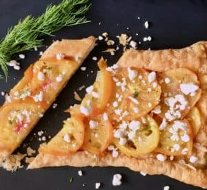 Sliced yellow tomato tart with feta and dill.