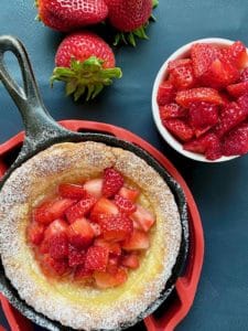 Strawberry kropsua in a cast iron pan with fresh strawberries.