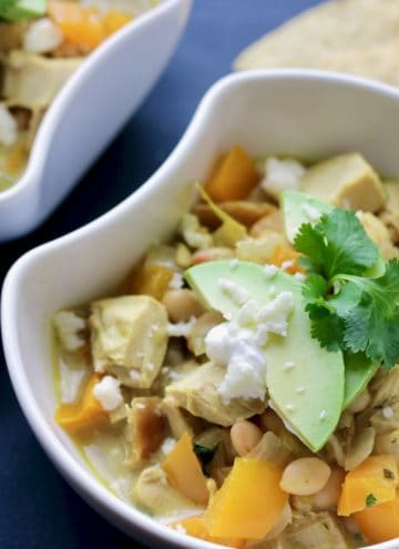 Bowl of Thai chicken chili topped with avocado and tortillas.