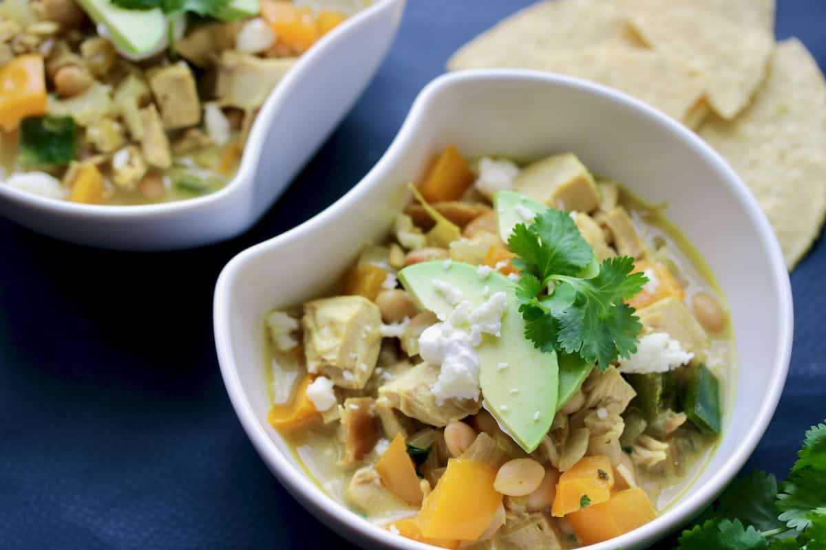 Bowl of Thai chicken chili topped with avocado and tortillas.