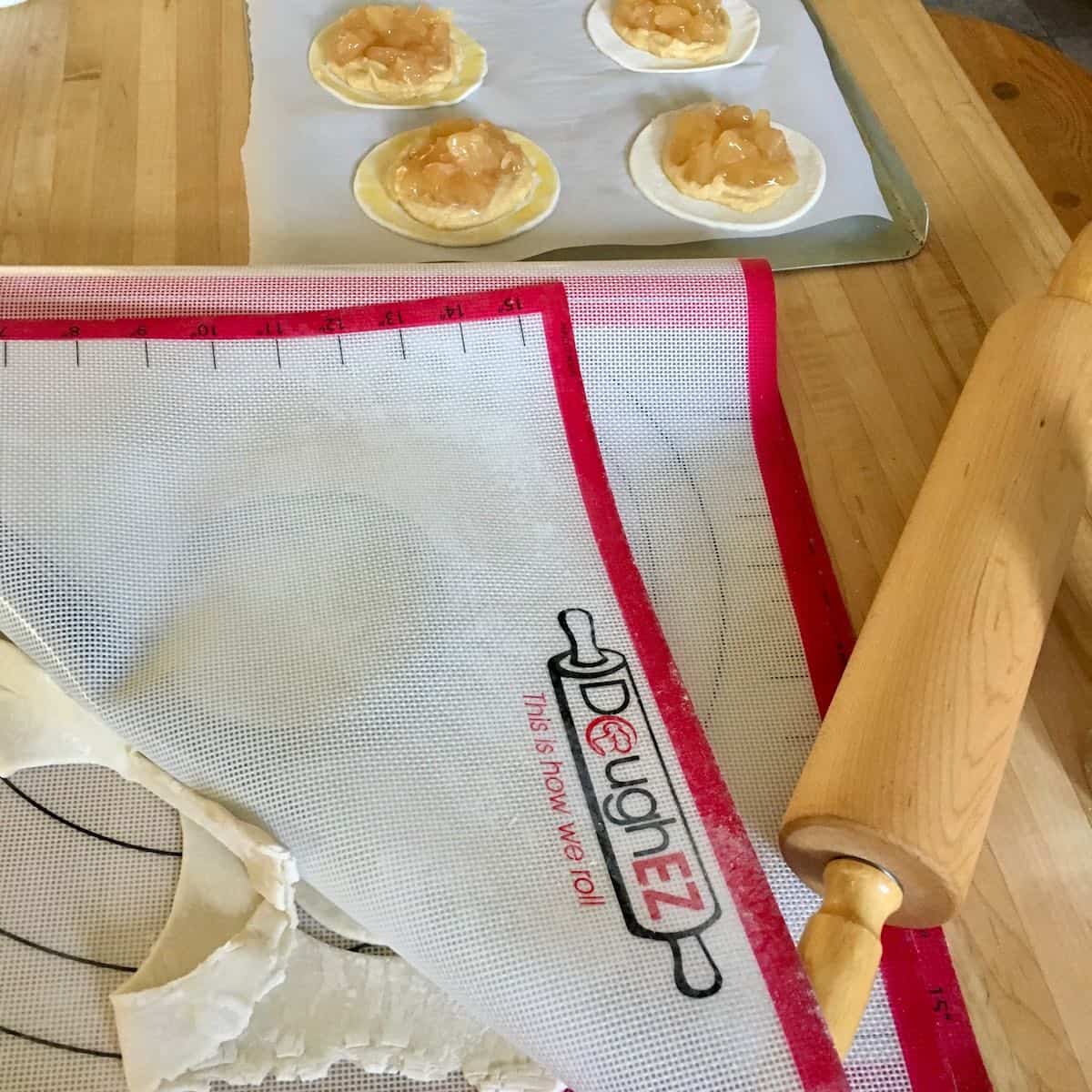 Apple filled pastries with rolling pin.