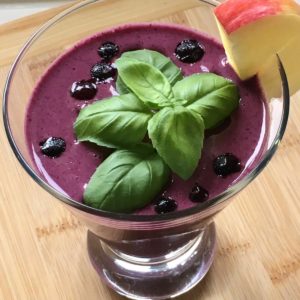 Wild blueberry smoothie garnished with basil and apple.