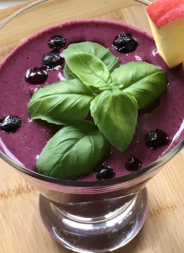 Wild blueberry smoothie garnished with basil and apple.
