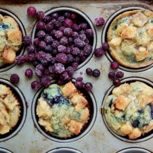 Maple blueberry muffins in muffin tin with wild blueberries.
