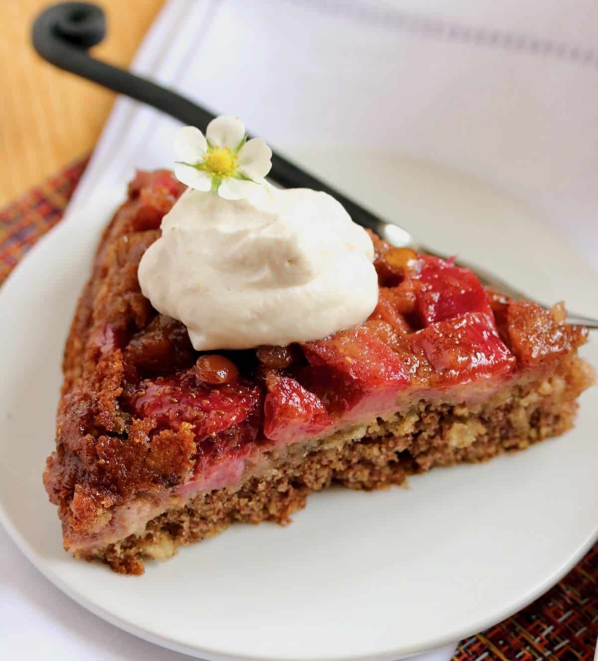 Slice of strawberry rhubarb skillet cake with whipped cream.