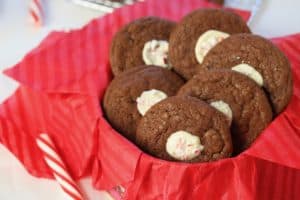 Good grief baking therapy includes peppermint stick cheesecake stuffed cookies in a cookie tin lined with red paper and a peppermint stick.