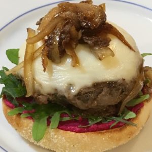 plated burger topped with cheese and onions