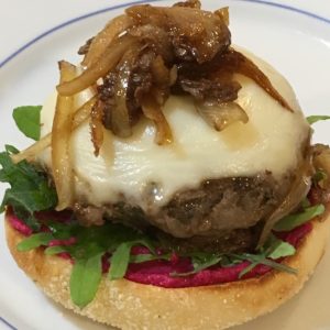 Plated mushroom blend burger topped with cheese and onions.
