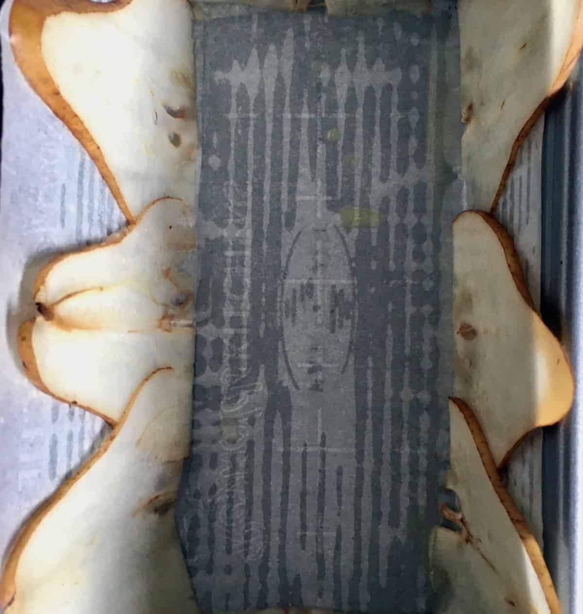 Lining pan with thinly sliced pears.