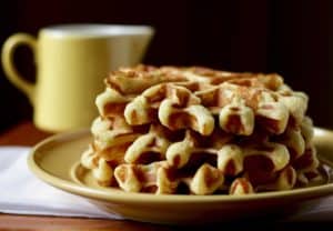 Stack of waffles with yellow syrup pitcher.