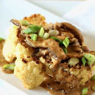 Plated cauliflower steak with lemon grass basil mushroom and green onion sauce.