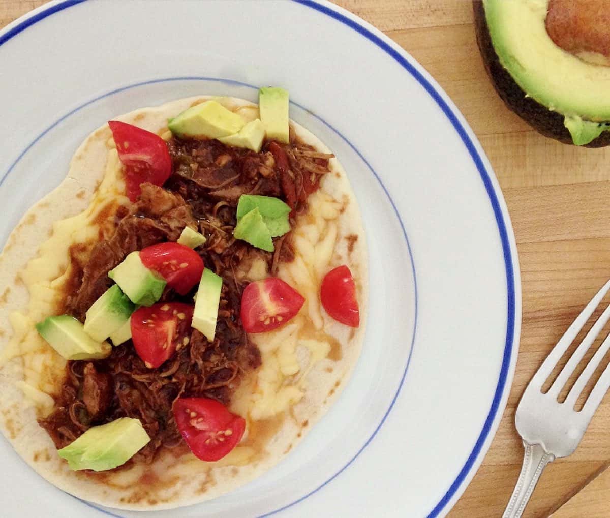 chicken mole on cheese tortilla with chopped avocado and tomatoes