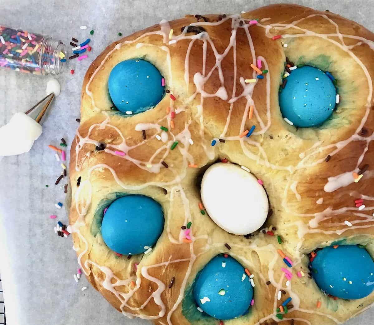Braided Easter bread with sprinkles and colored eggs.