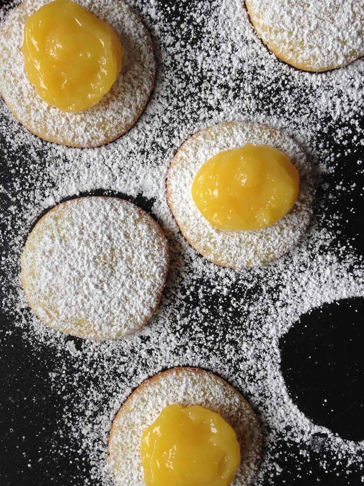 Lemon curd on cookies dusted with powdered sugar.