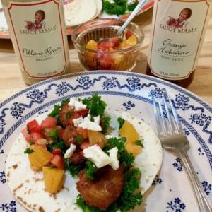 Plated unexpected shrimp tacos with product bottles.
