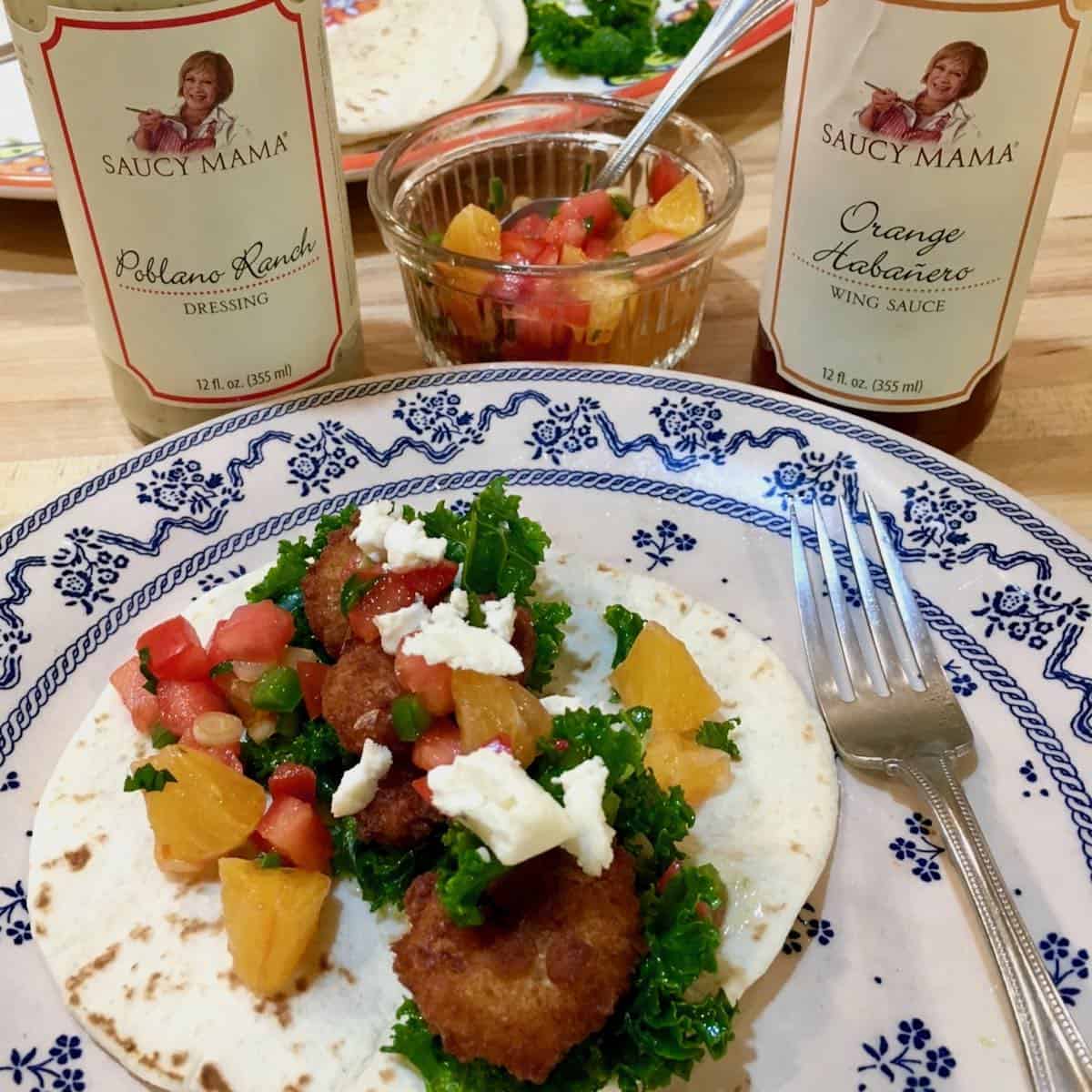 Plated unexpected shrimp tacos with product bottles.