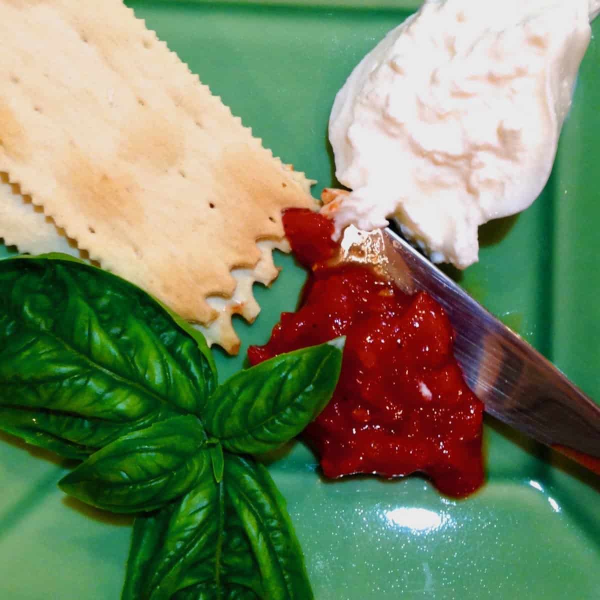 A new caprese plate of mozzarella, crackers and jam and basil.