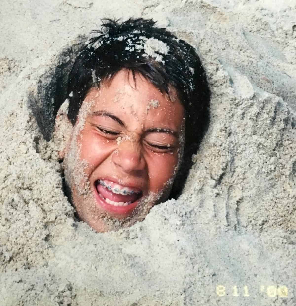 Young William buried in the beach sand.