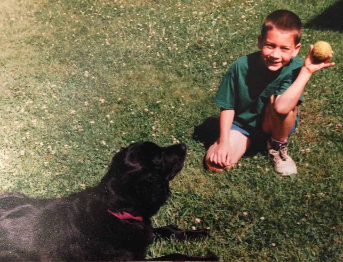 Go fetch my son tossing ball to dog.