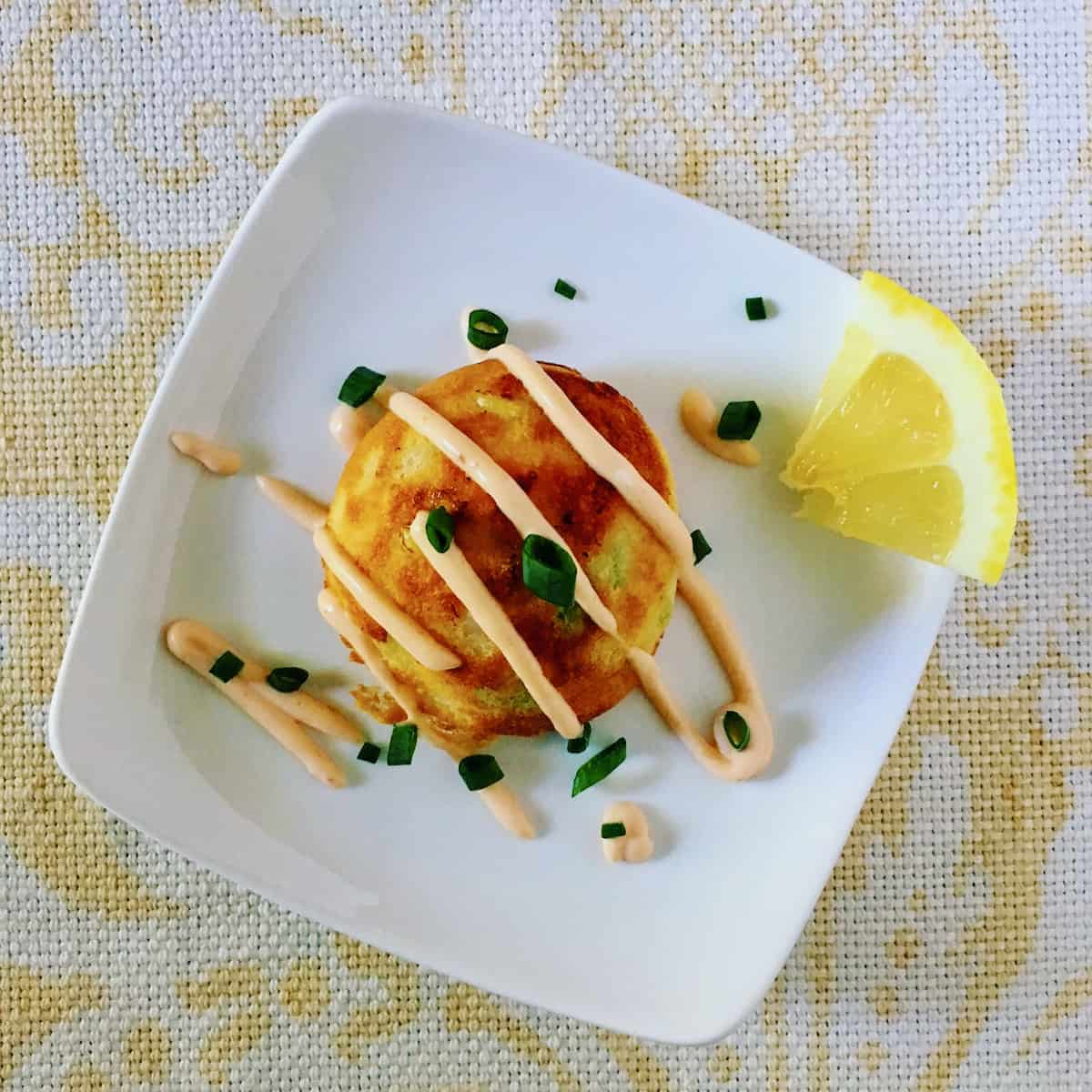 Lobster corn chowda cakes with lemon wedge.