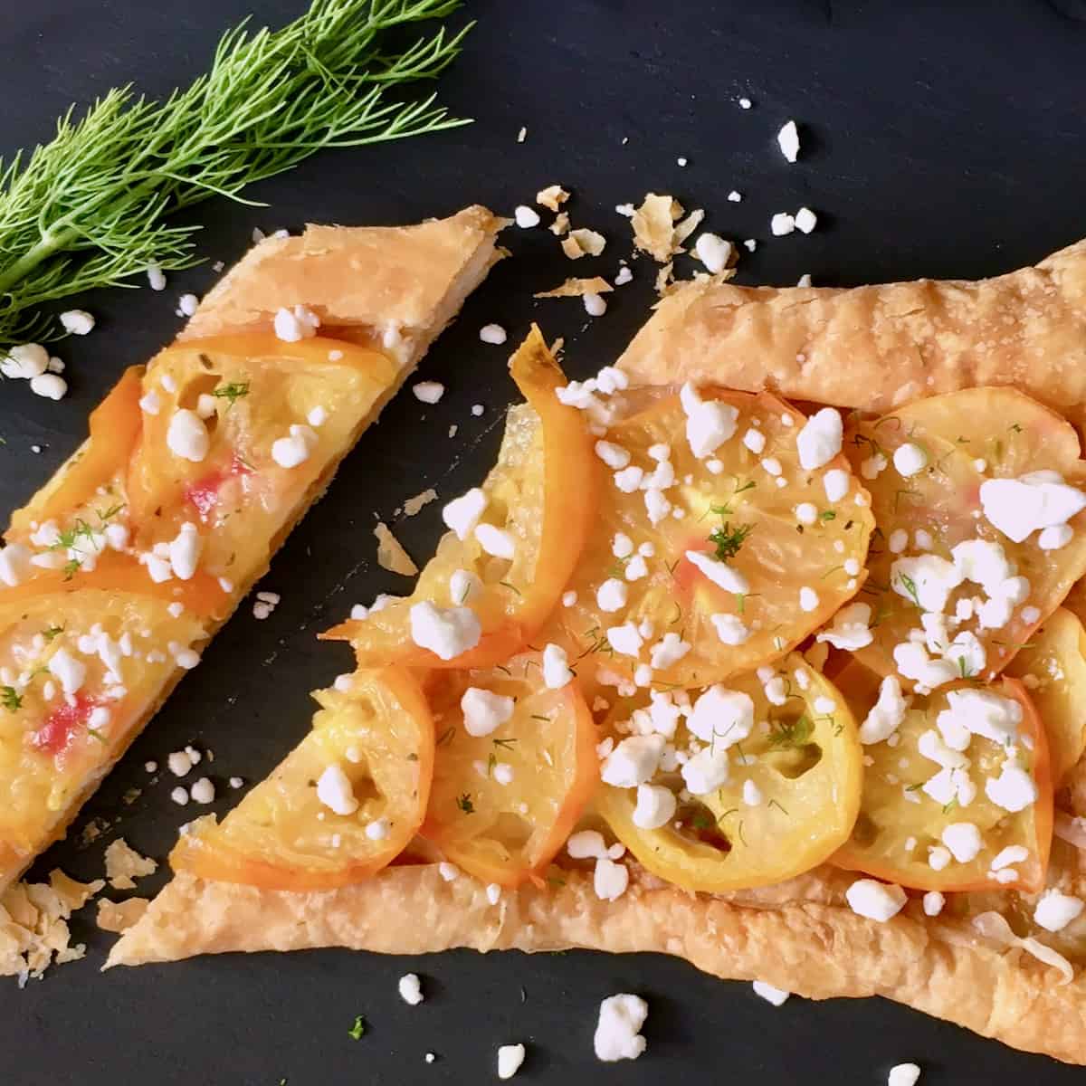 Sliced yellow tomato tart with feta and dill.
