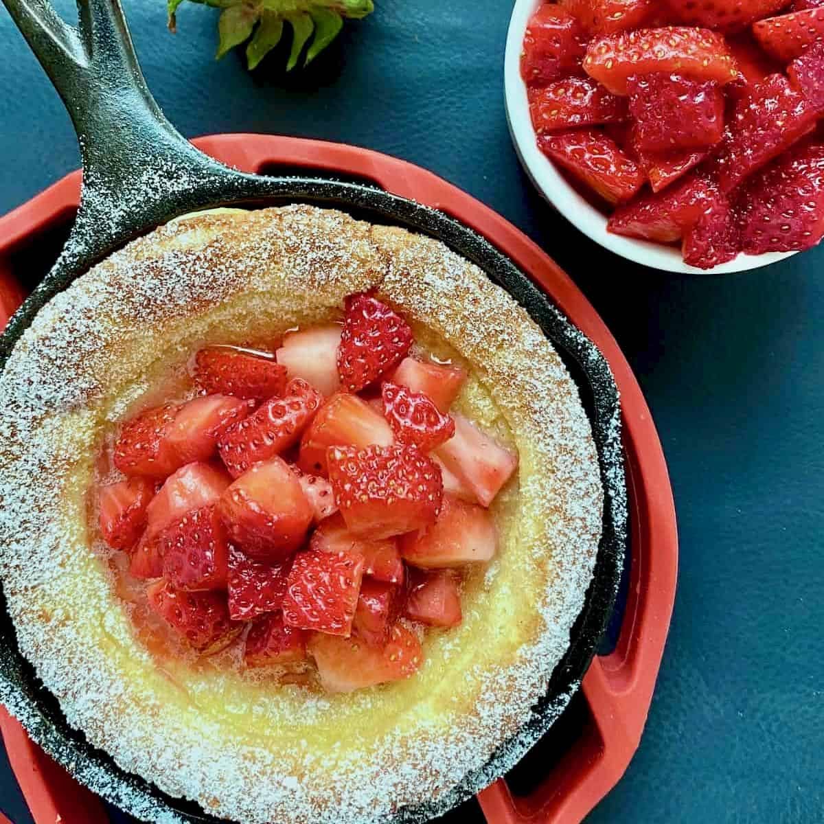 Strawberry kropsua in a cast iron pan with fresh strawberries.