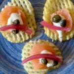 Easy smoked salmon appetizer. Smoked salmon on waffle potato chip with capers, pickled onion and sauce.