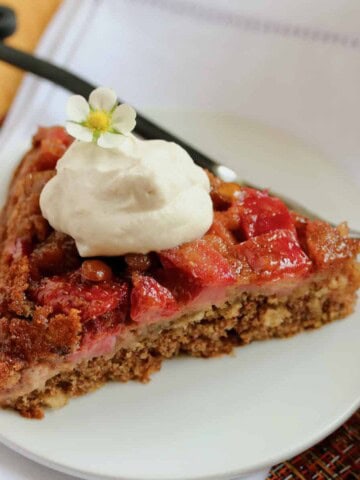 Slice of strawberry rhubarb skillet cake with whipped cream.
