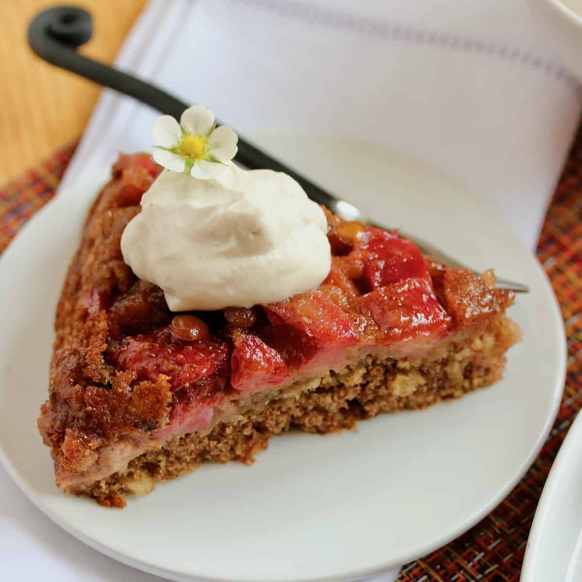 Slice of strawberry rhubarb skillet cake with whipped cream.