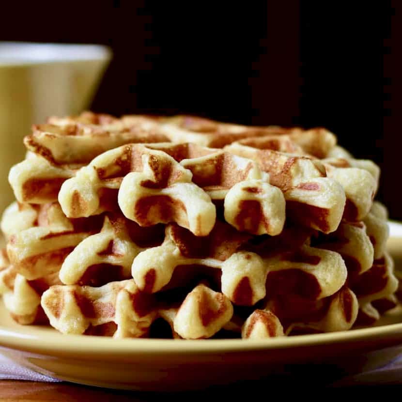 Stack of waffles with yellow syrup pitcher.