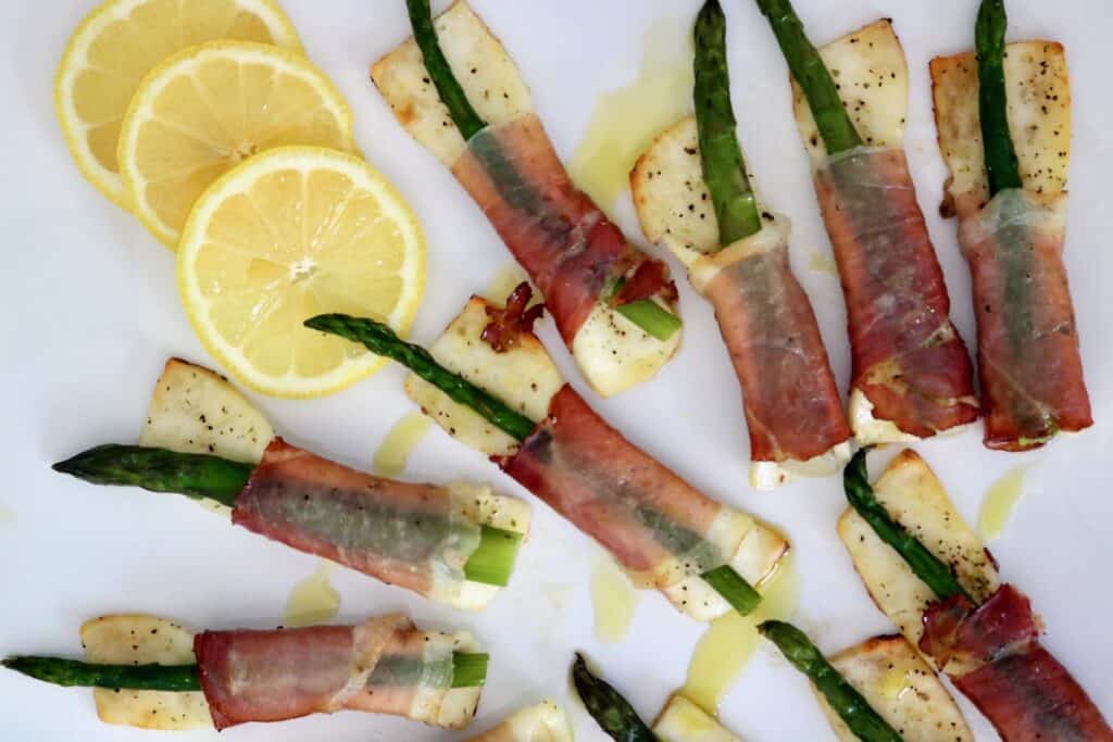 Paneer, proscuitto & asparagus tapas on serving platter with lemon slices.