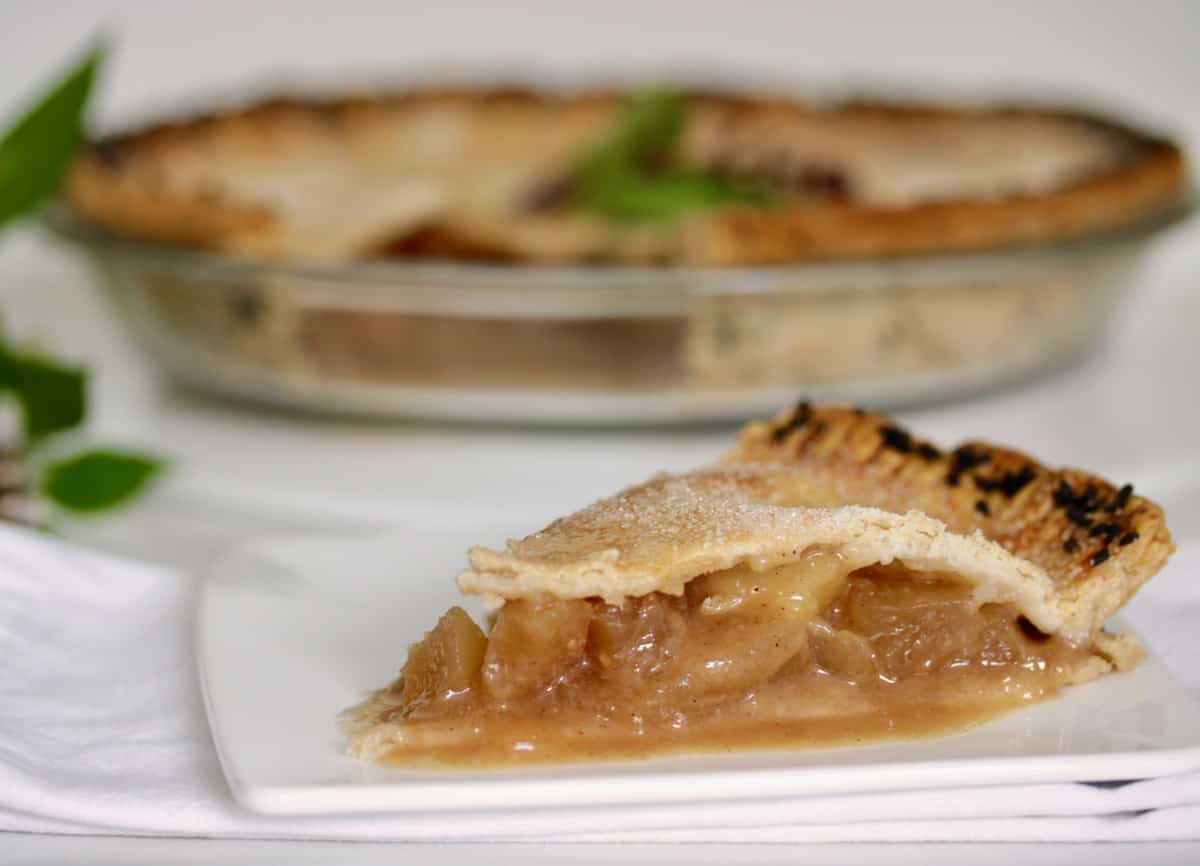 A slice of Five-Spice Miso Caramel apple pie with black sesame crust.
