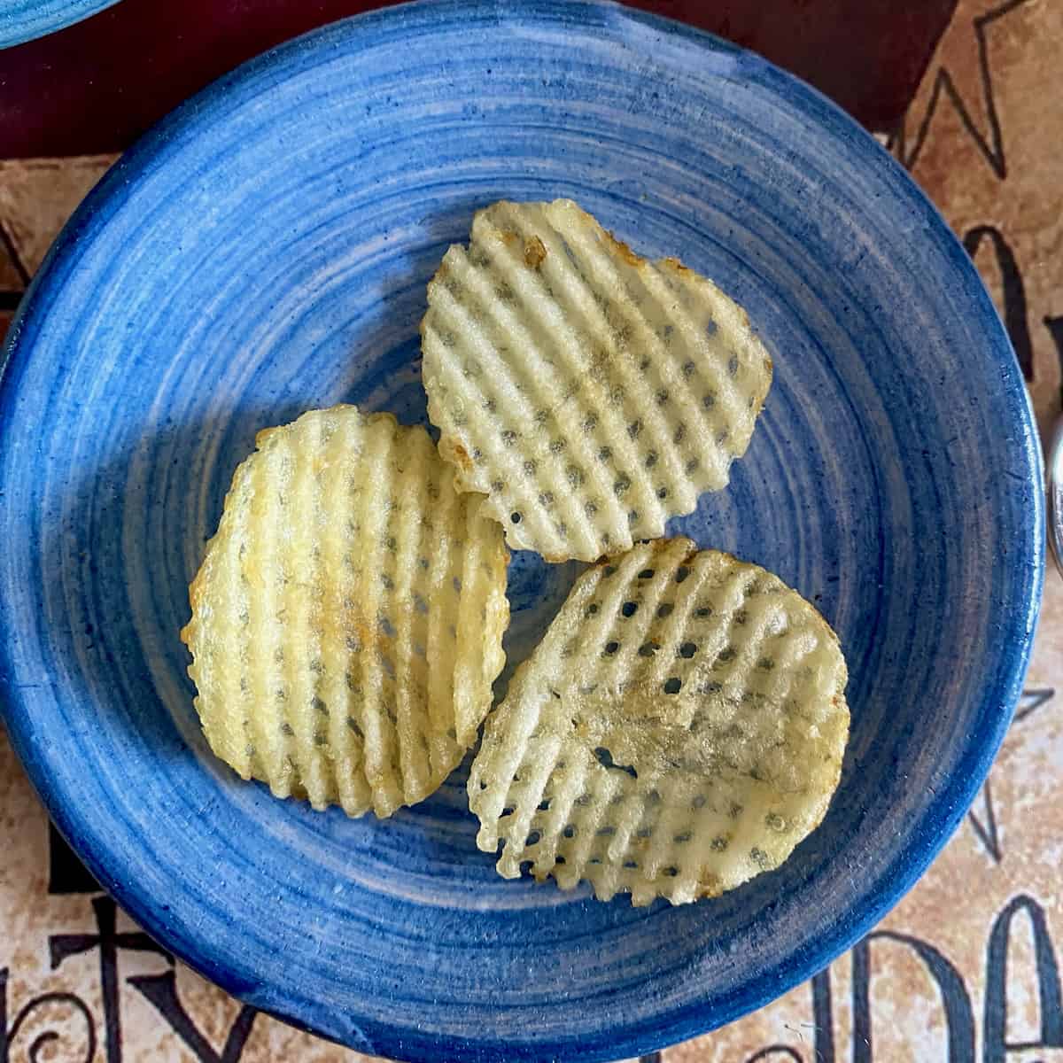 Waffle potato chips on blue plate.