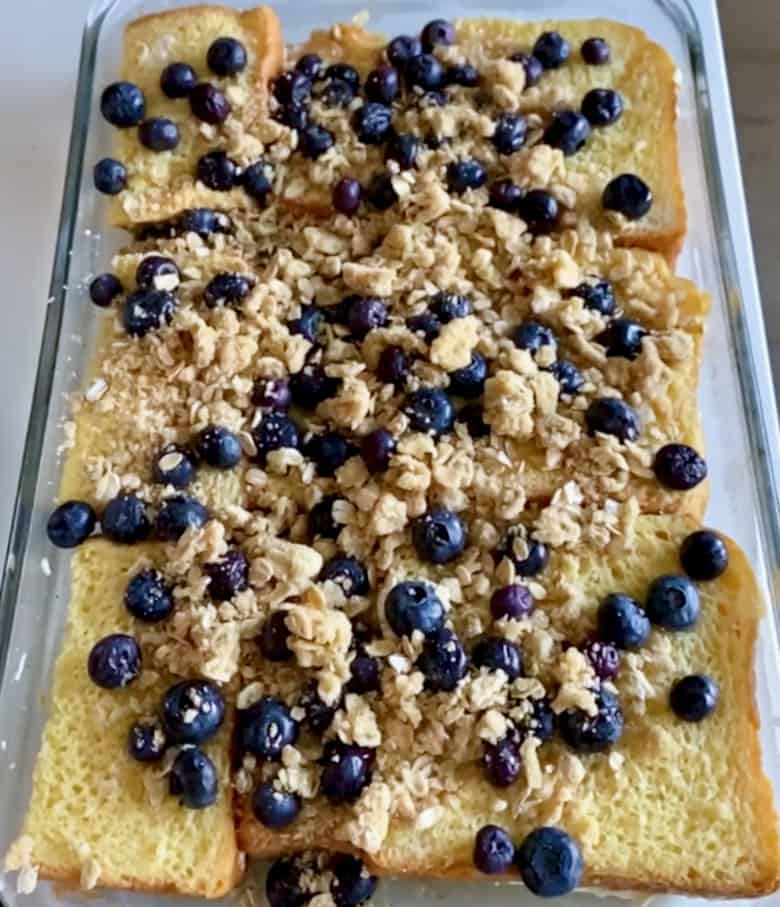 Layers of brioche stuffed bread and blueberry crumble in baking dish.