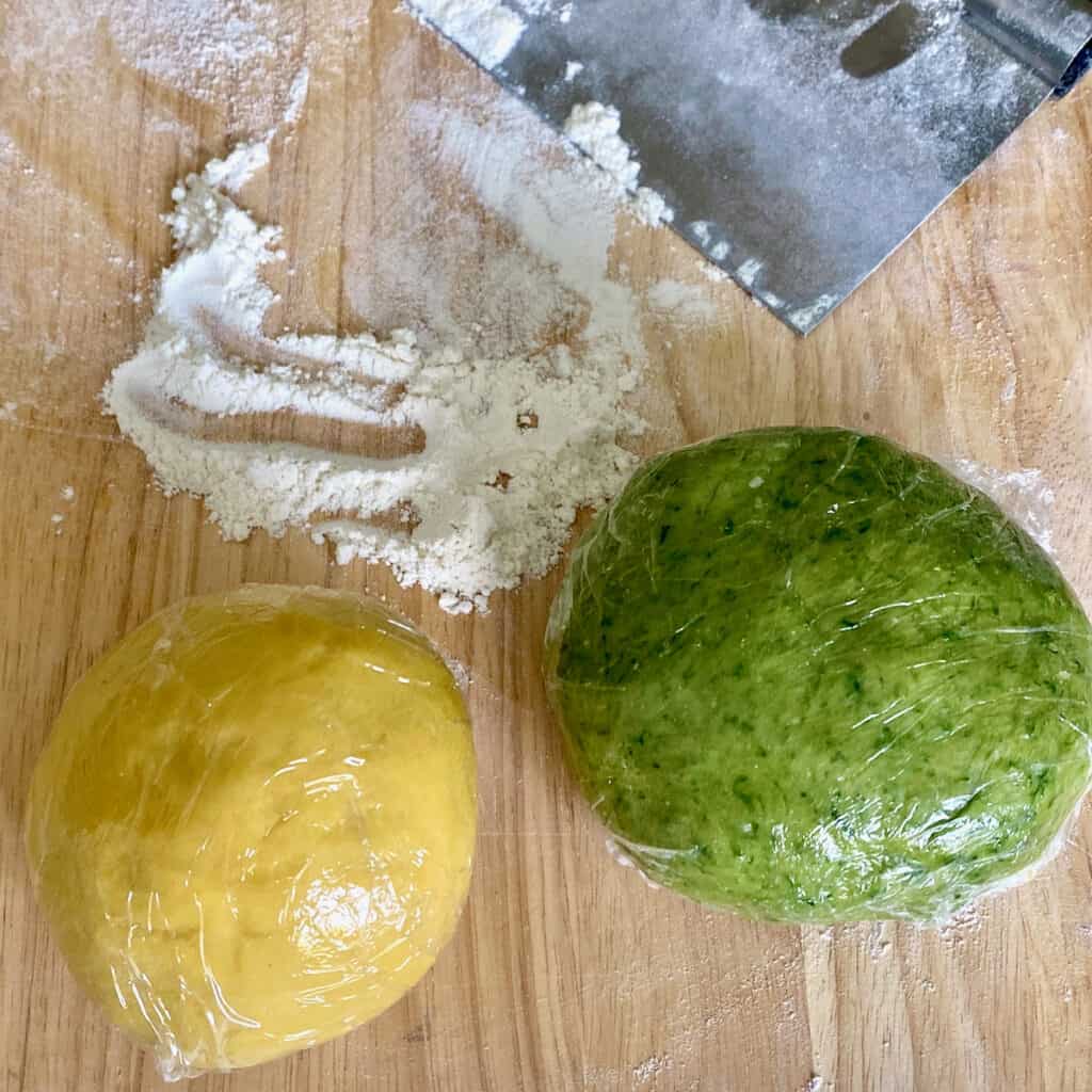 Plain pasta dough and ramp pasta dough resting on floured board.