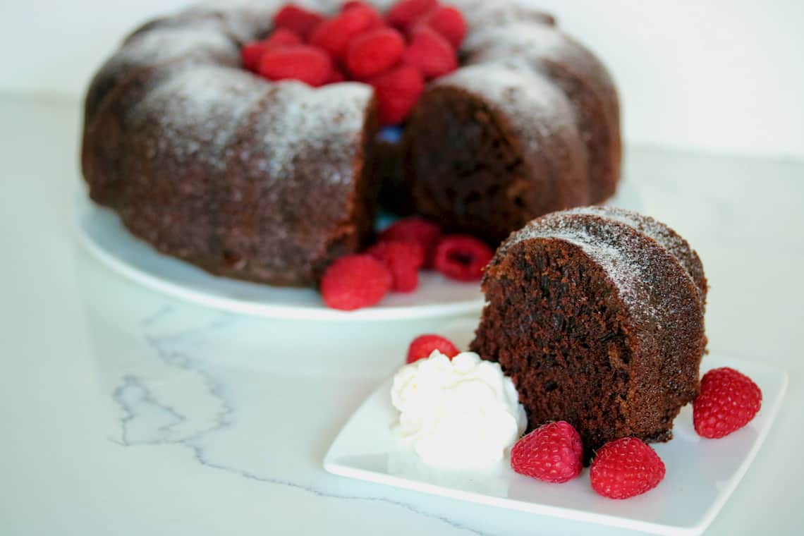 Slice of cake with raspberries and whipped cream.