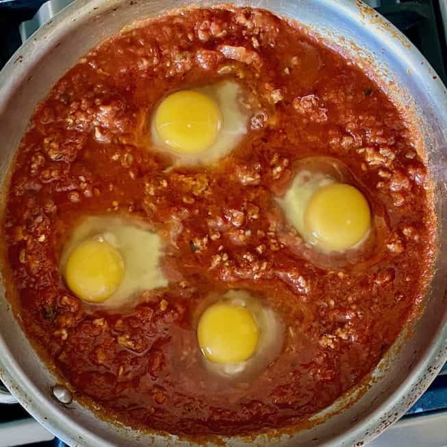 Poaching the eggs in the sauce.