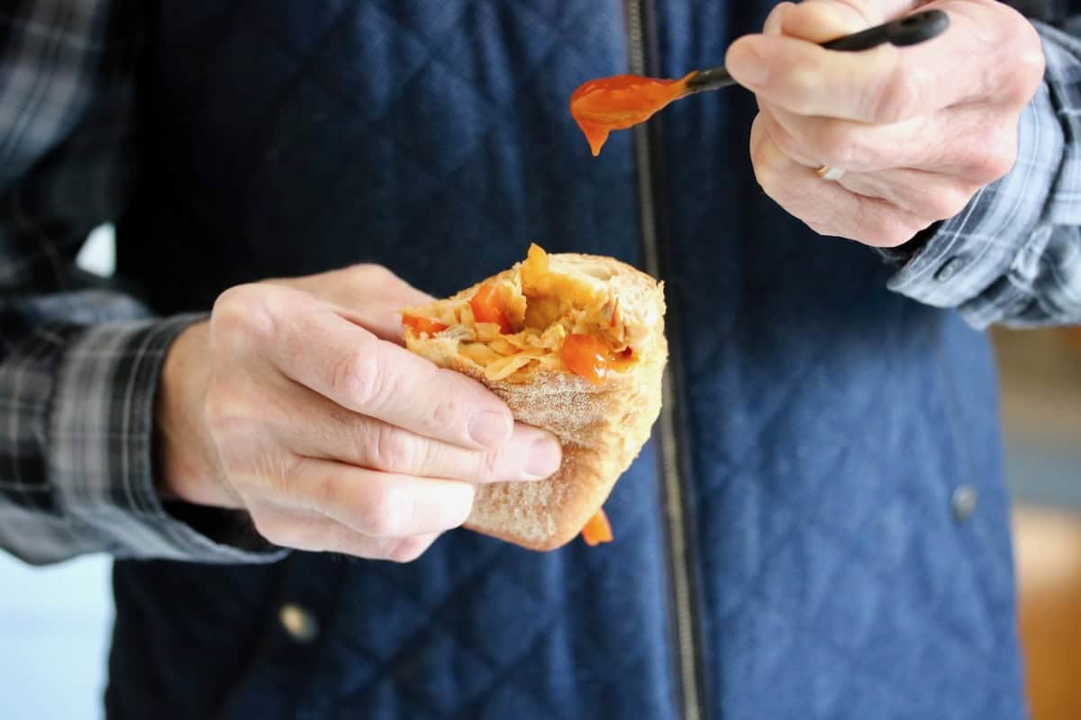 Adding extra sauce to the sandwich.
