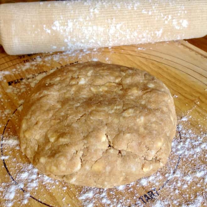 Pie dough on floured board with rolling pin.
