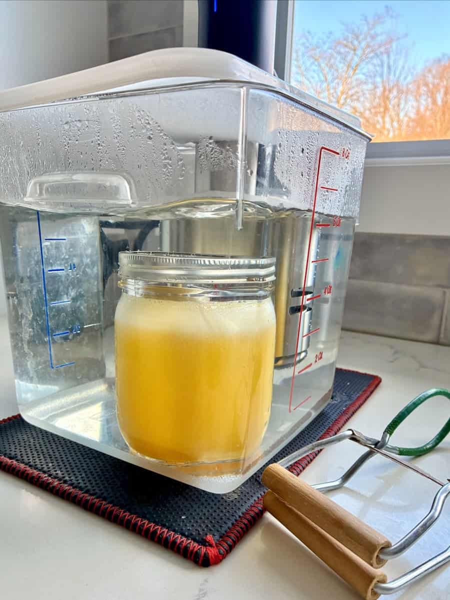 Immersion circulator cooking a jar of curd.