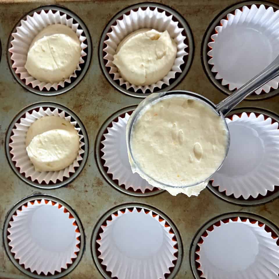 Filling cupcake liners with an ice cream scoop.