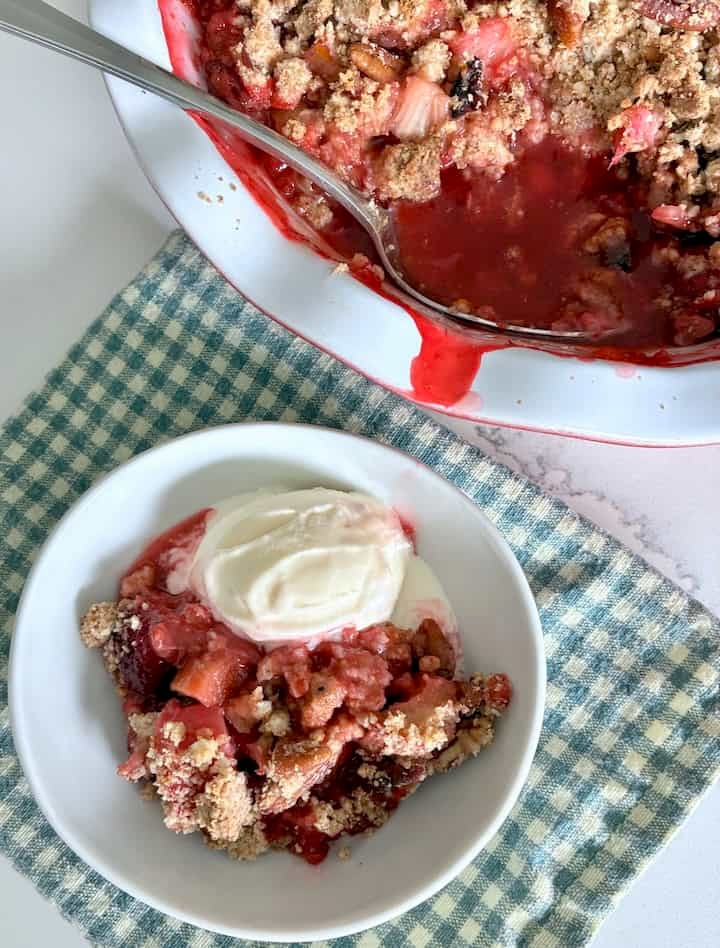 A serving of strawberry rhubarb crumble with ice cream.