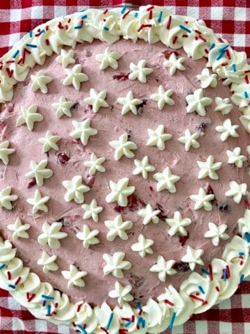 Birthday pie with whipped cream stars and sprinkles on a checkered tablecloth.