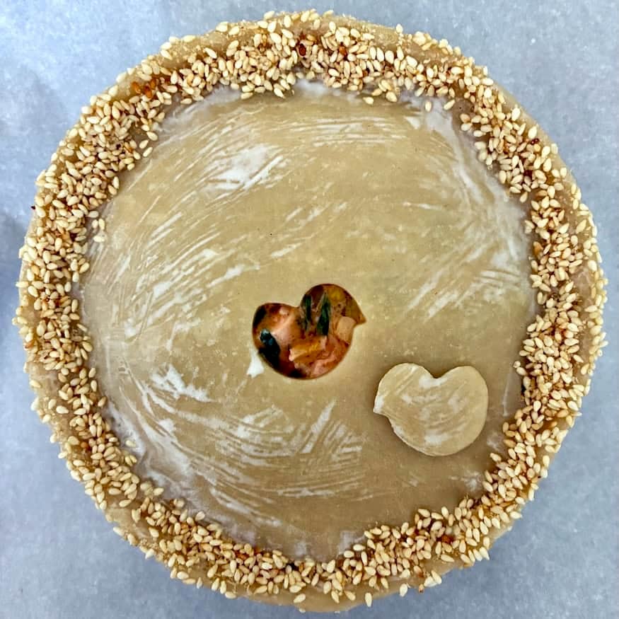 Heavy cream wash on top pie crust with sesame seed edge and dough cut out.