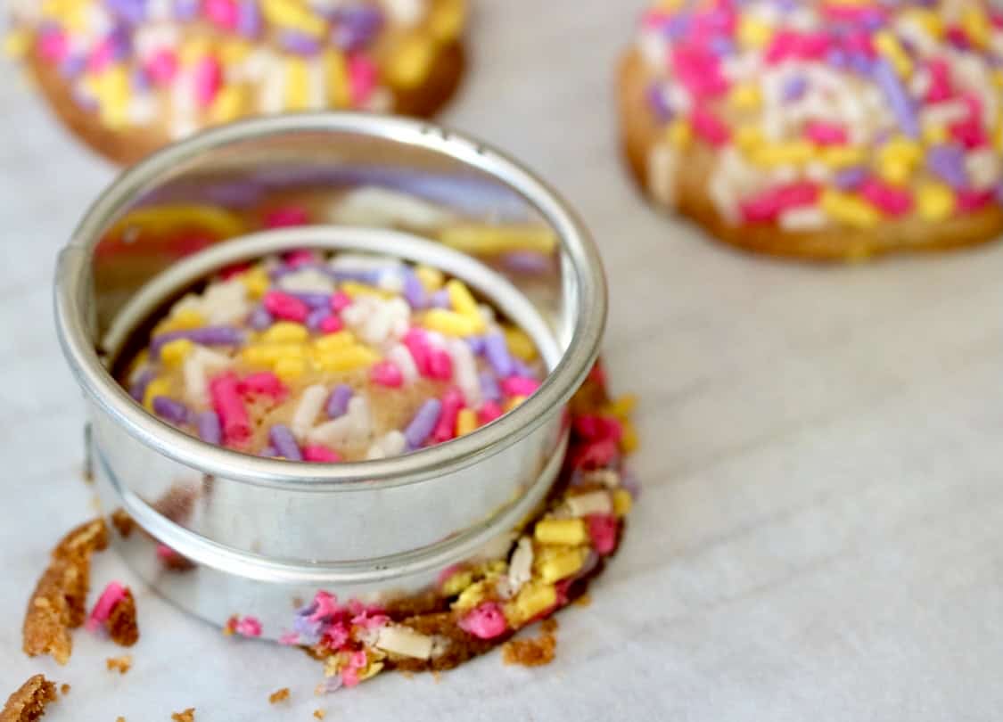 Cutting sprinkle cookies into round shapes.