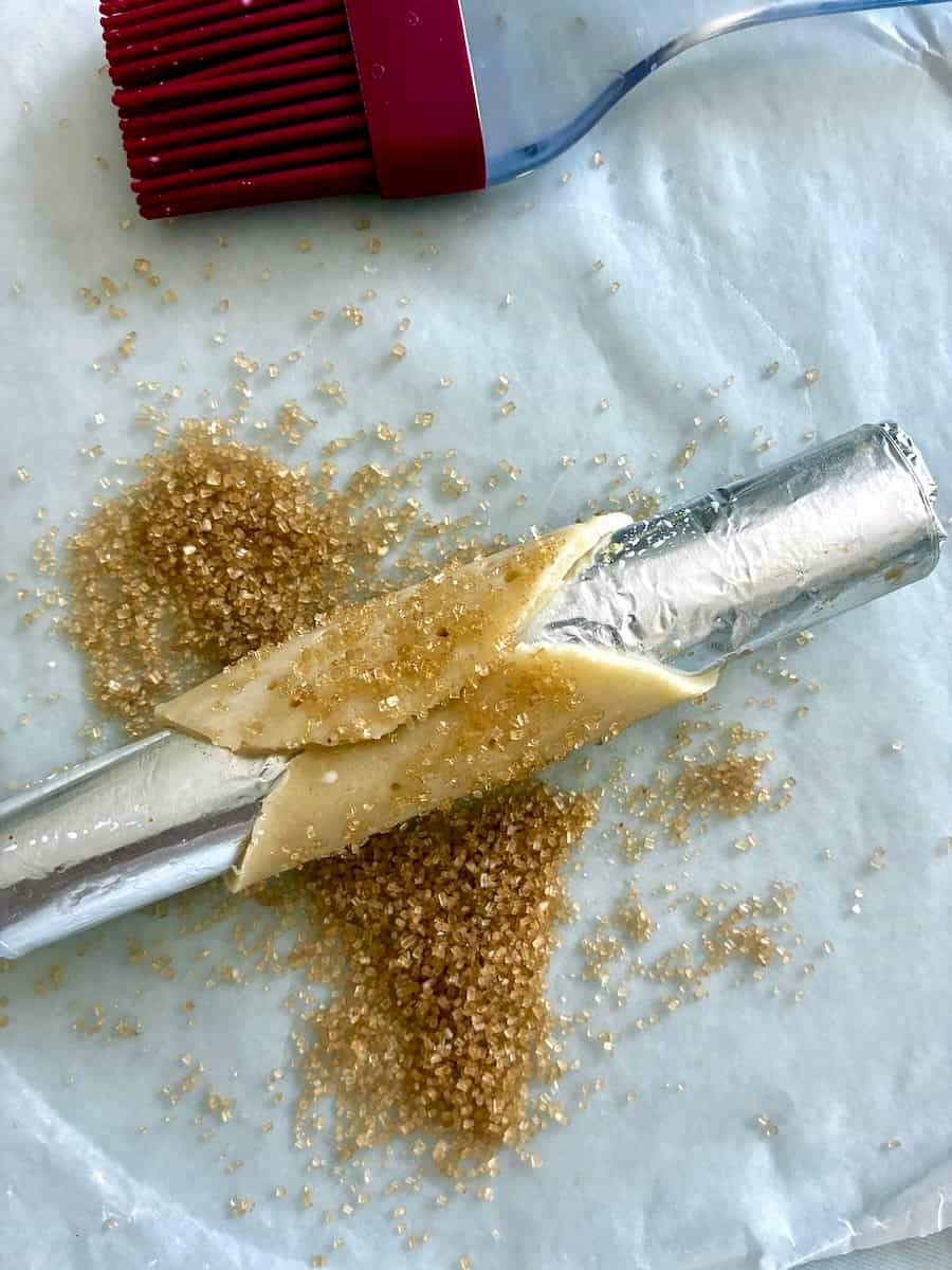 Forming cannoli shells and coating with sugar.