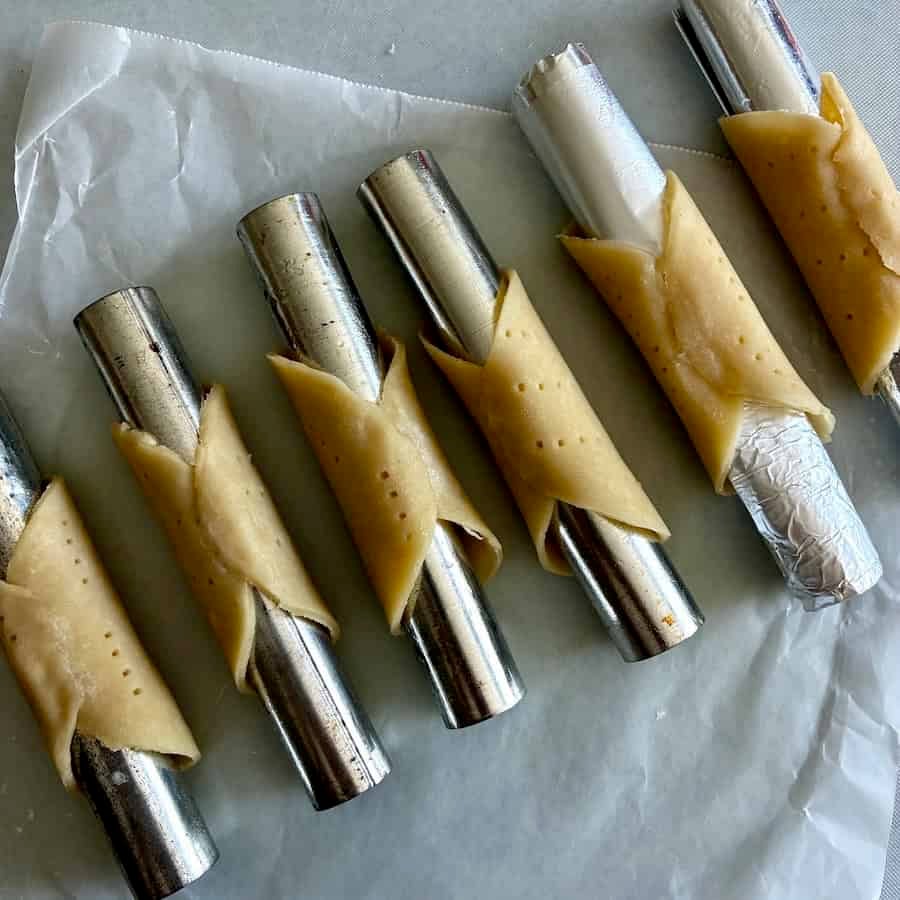 Pie crust cannoli shells on forms.