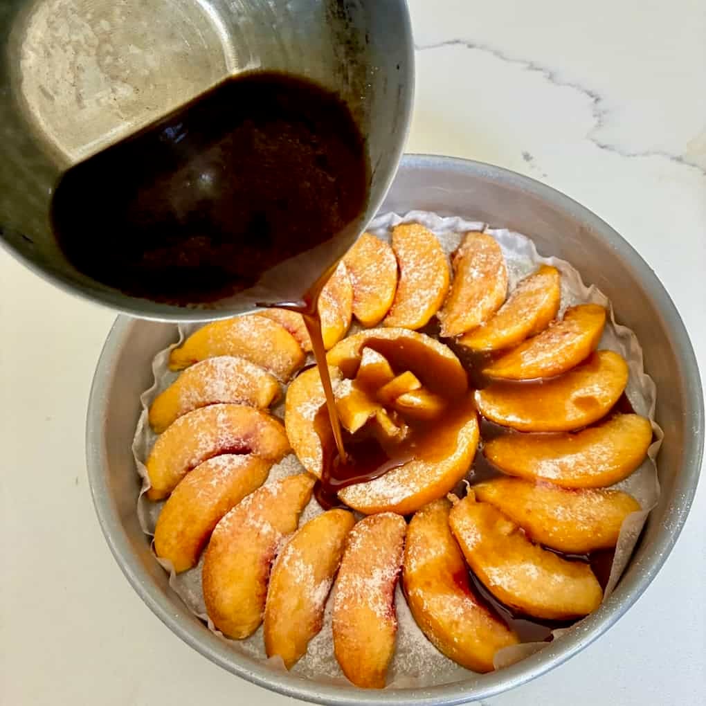 Bourbon caramel poured over peaches in pan.