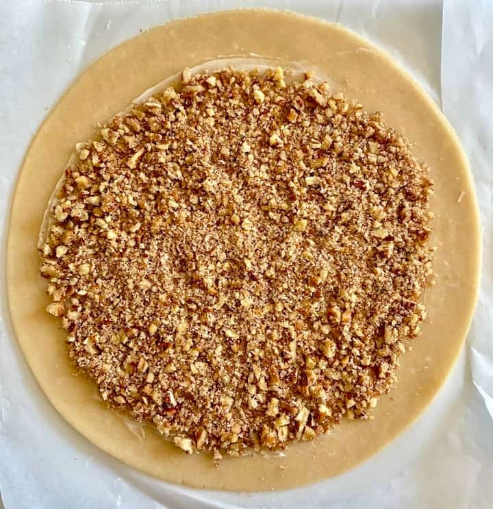 Pecan filling on buttered pie dough circle.
