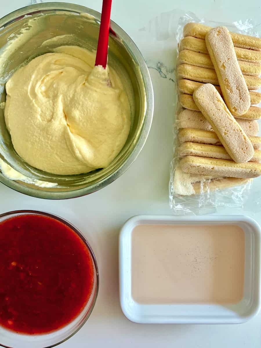 Dessert ingredients including mascarpone cream, ladyfingers, rhubarb syrup and strawberry sauce.